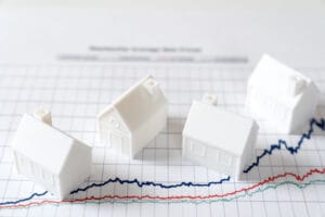 Illustration de maisons miniatures sur un graphique représentant la variation des taux d’emprunt immobilier en 2025.