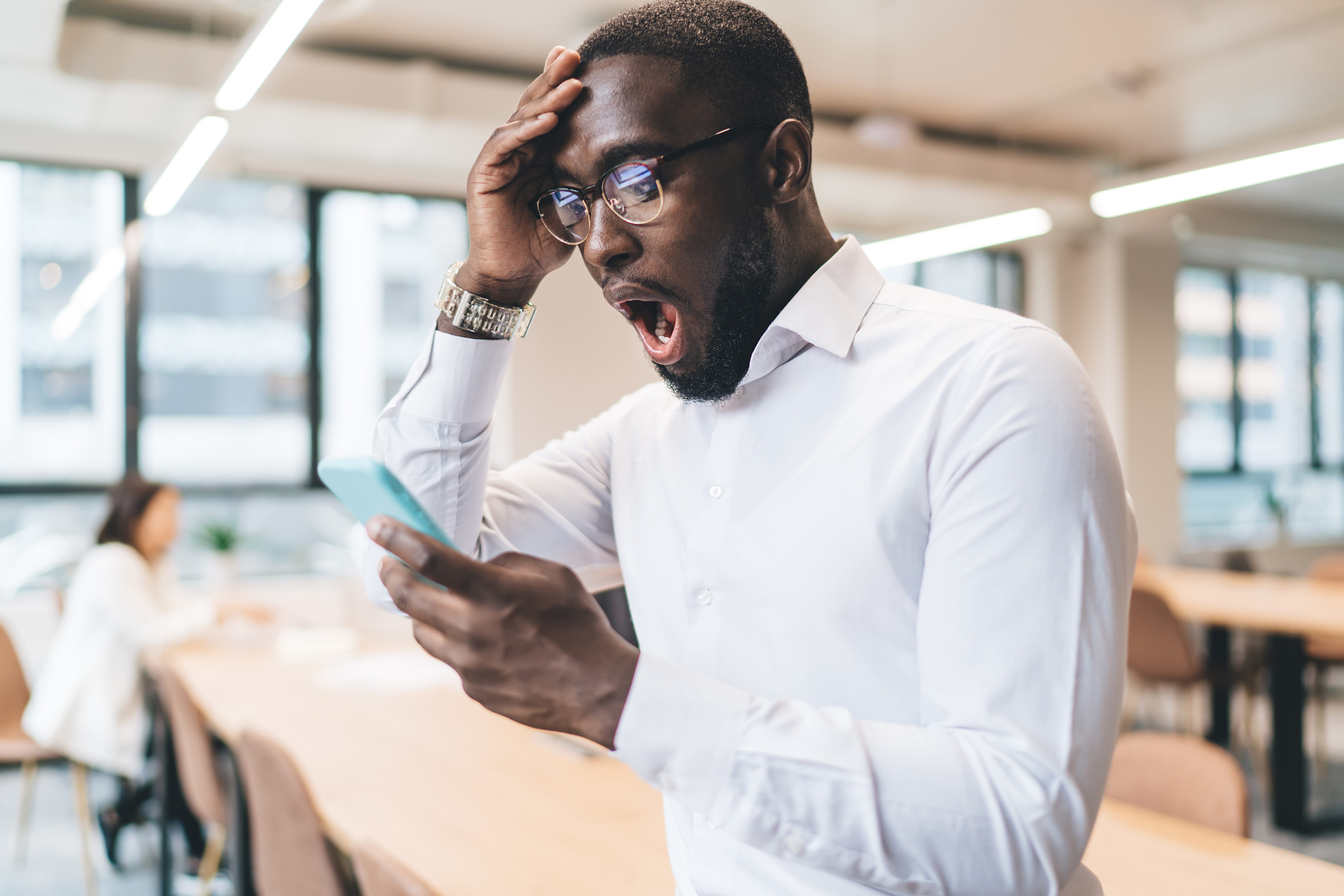 Un homme surpris lit des frais cachés de forfaits mobiles sur son smartphone