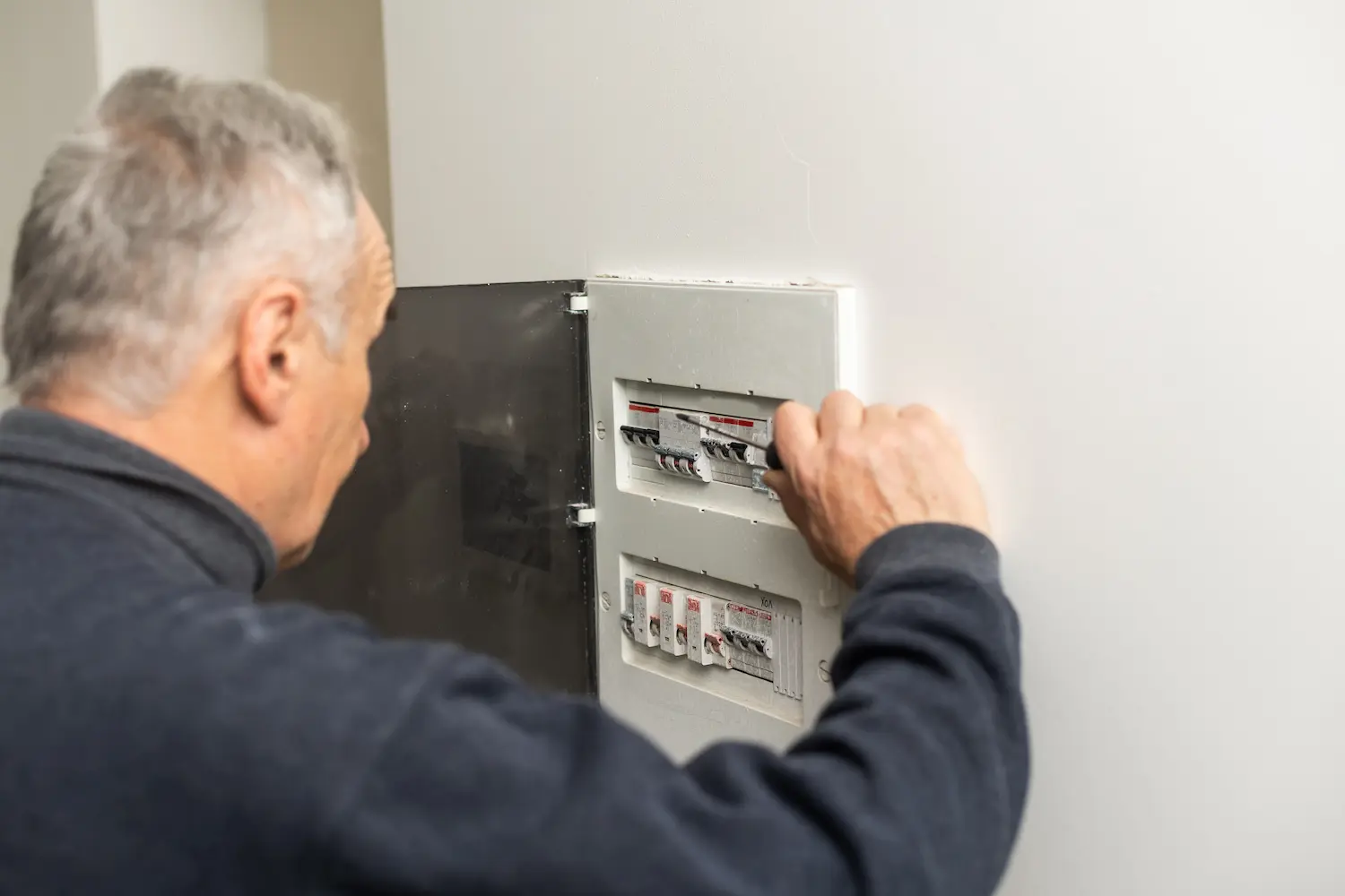 homme devant son panneau électrique ayant disjoncté plusieurs fois d'affilé