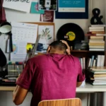 étudiant de dos stressé sur son bureau dans son studio à cause de sa facture d'électricité