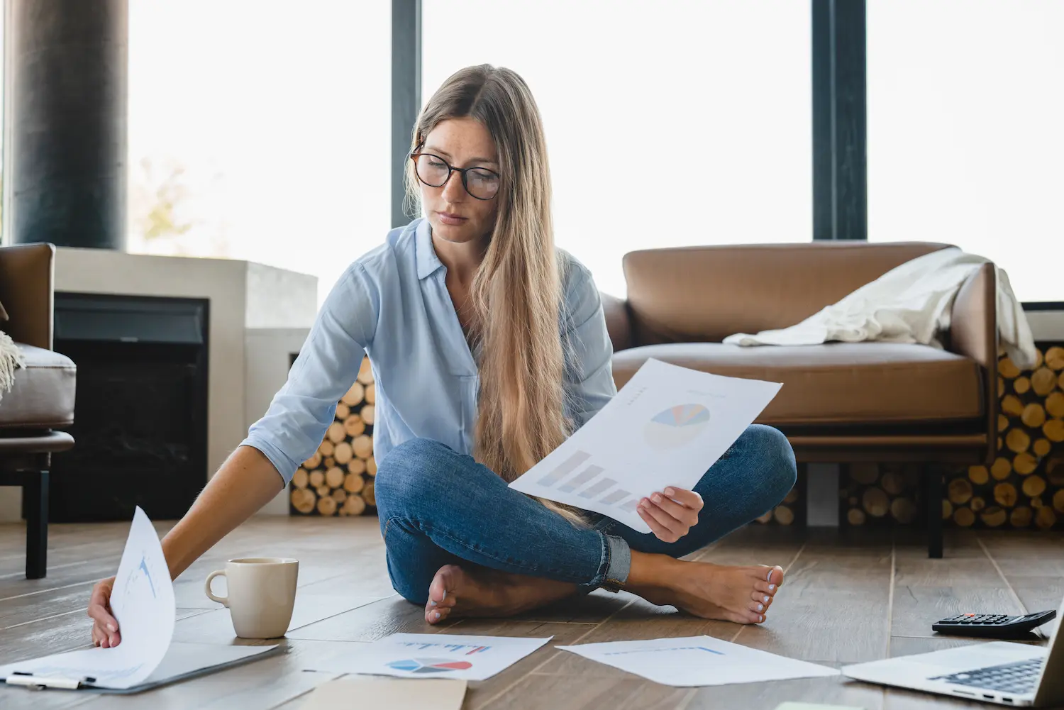 femme assise sur le sol de son appartement analysant les factures de l'année de son contrat Tempo
