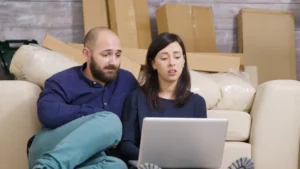 un couple au milieu des cartons de déménagement compare les offres de contrat d'électricité avant leur emménagement