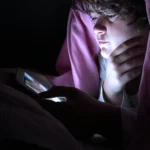 un adolescent regardant sa tablette sous sa couette qui a un problème de connexion