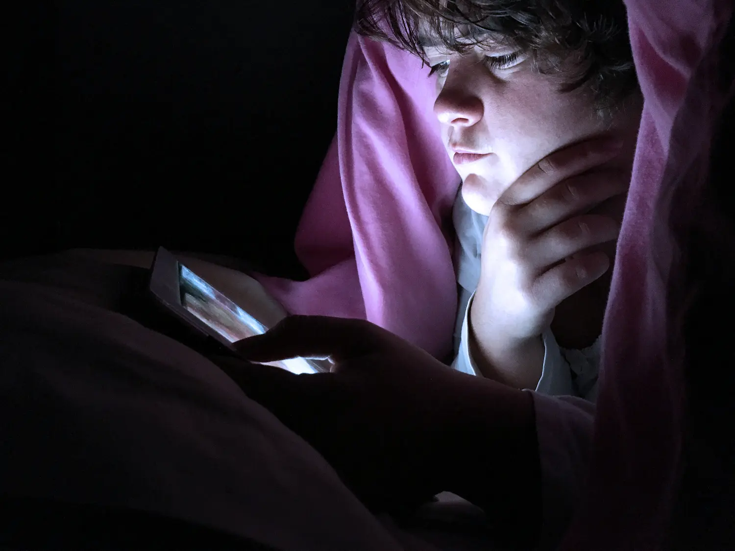 un adolescent regardant sa tablette sous sa couette qui a un problème de connexion