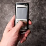 homme tenant dans sa main gauche un téléphone à clapet 3G