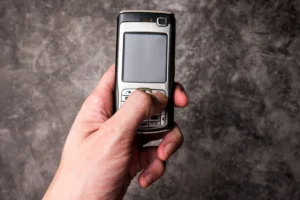 homme tenant dans sa main gauche un téléphone à clapet 3G